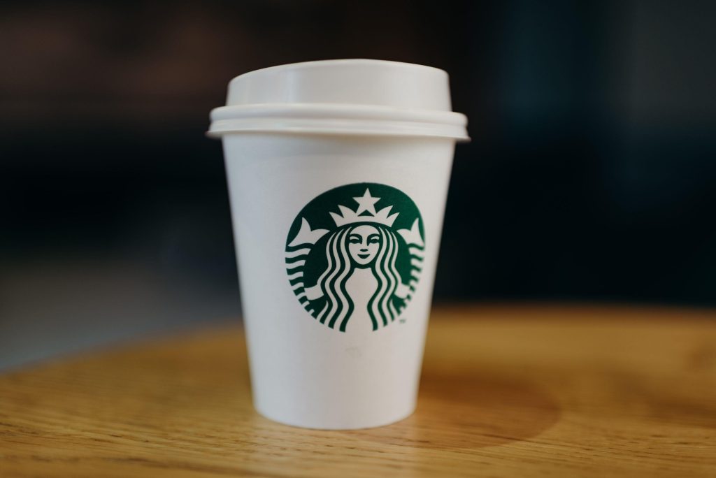 Kopje pumpkin spice latte met kaneelstokje en pompoen decoratie op herfstachtergrond